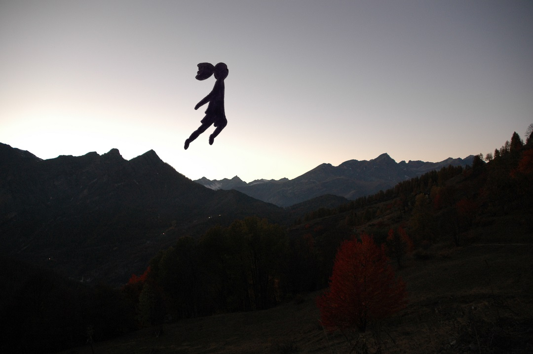 Decorative divider: Dark silhouette of Flying Amrita leaping over the Alpine ridge of Marmora. Inspired by Natsumi Hayashi's photography, the image symbolizes a leap toward freedom and the spirit of the Amrita Express project.